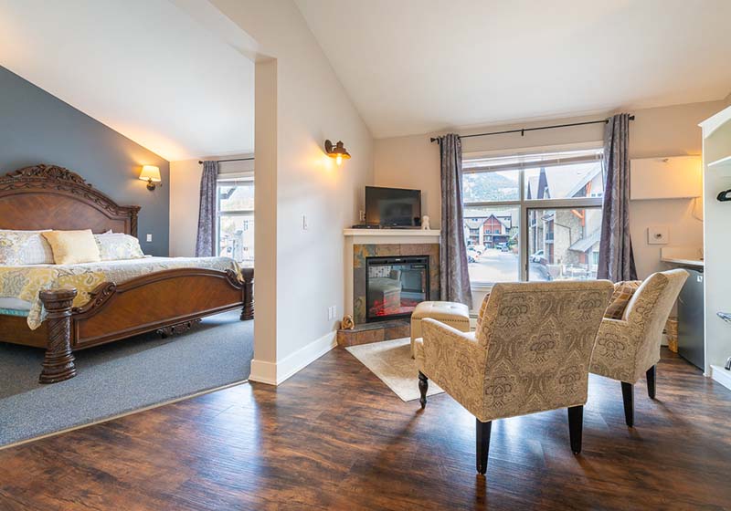 A large king bed inside one of our Regency Suite rooms with a desk looking out the sunlit window.